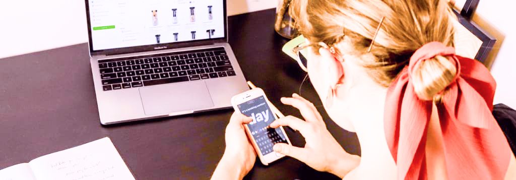 Photo of woman in orange shirt using iphone and laptop